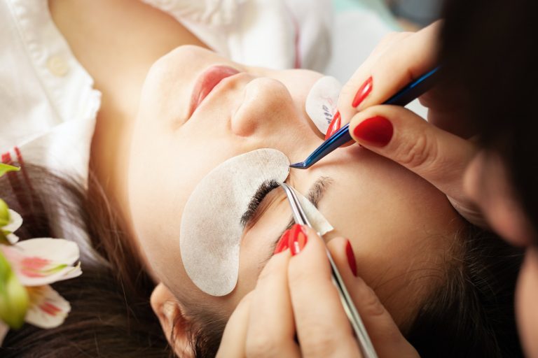 Eyelash extensions in a beauty salon. A young girl lies on a couch